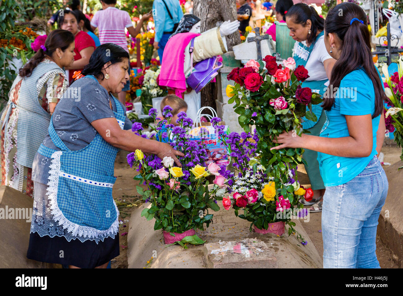 Les gens avec des tombes décorées une pédale floral tapisseries en l'honneur du défunt au cimetière San Antonino Castillo pendant le jour de la Fête des Morts connus sous le nom d'un de muertos le 3 novembre 2013 à San Antonino Castillo Velasco, Oaxaca, Mexique. Banque D'Images