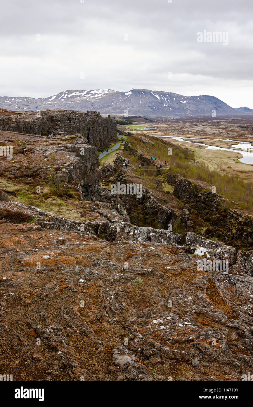 Les gens qui marchent à travers les fissures dans les plaques continentales au parc national de thingvellir Islande Banque D'Images