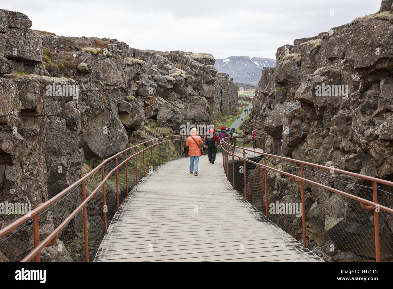 Personnes marchant vers le bas à travers les fissures dans les plaques continentales au parc national de thingvellir Islande Banque D'Images
