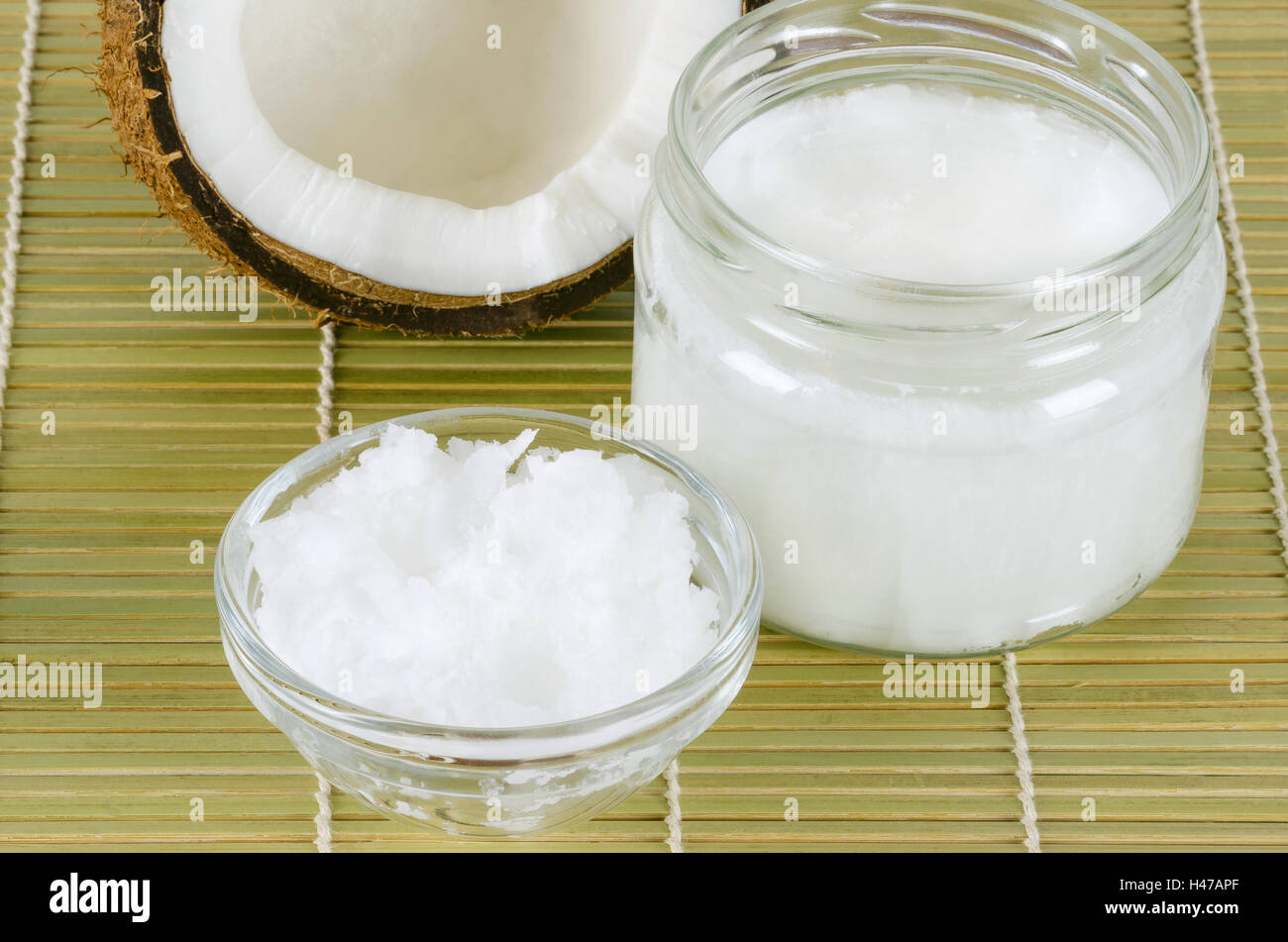 L'huile de noix de coco dans les verres sur le tapis de bambou horizontal. Extra vierge biologique huile de coprah. L'huile comestible, extrait de viande de coco. Banque D'Images