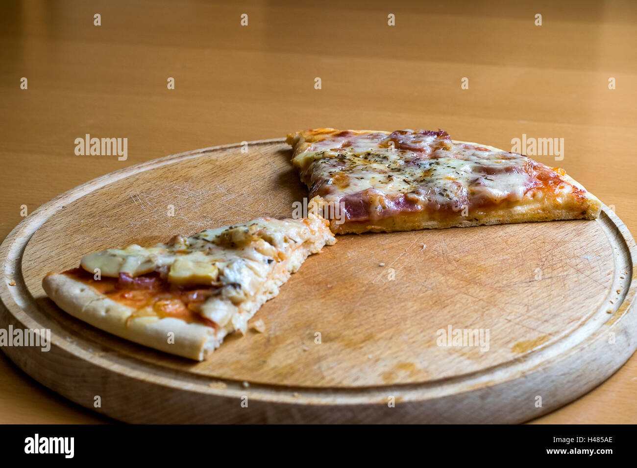 Les restes de morceaux de pizza sur une planche à découper en bois Banque D'Images