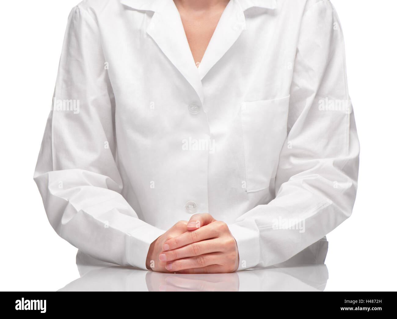 Portrait de femme en robe blanche assise à table contre fond blanc Banque D'Images