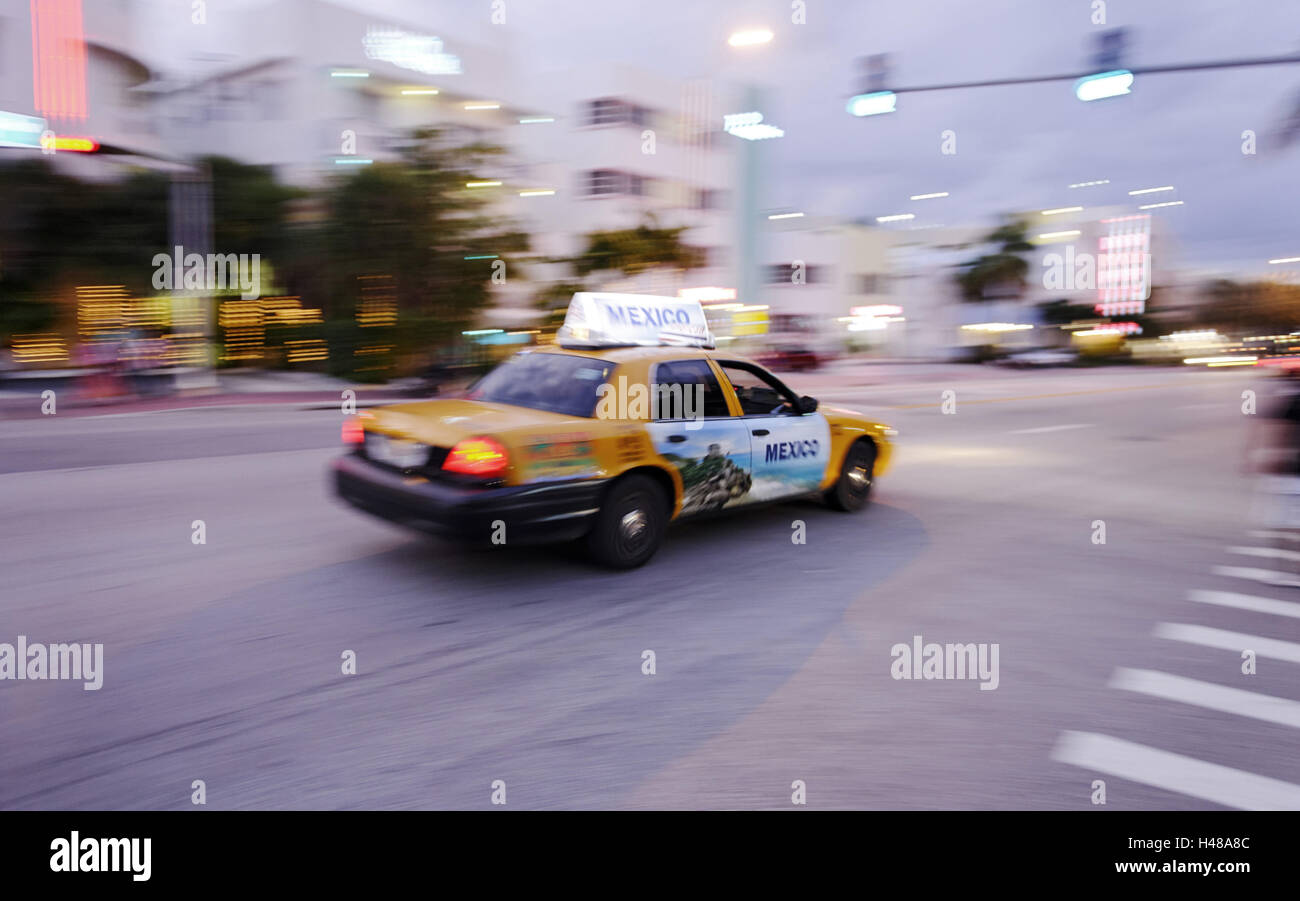 Taxi à pleine vitesse en début de soirée sur Collins Avenue, Miami South Beach, quartier Art déco, Florida, USA, Banque D'Images