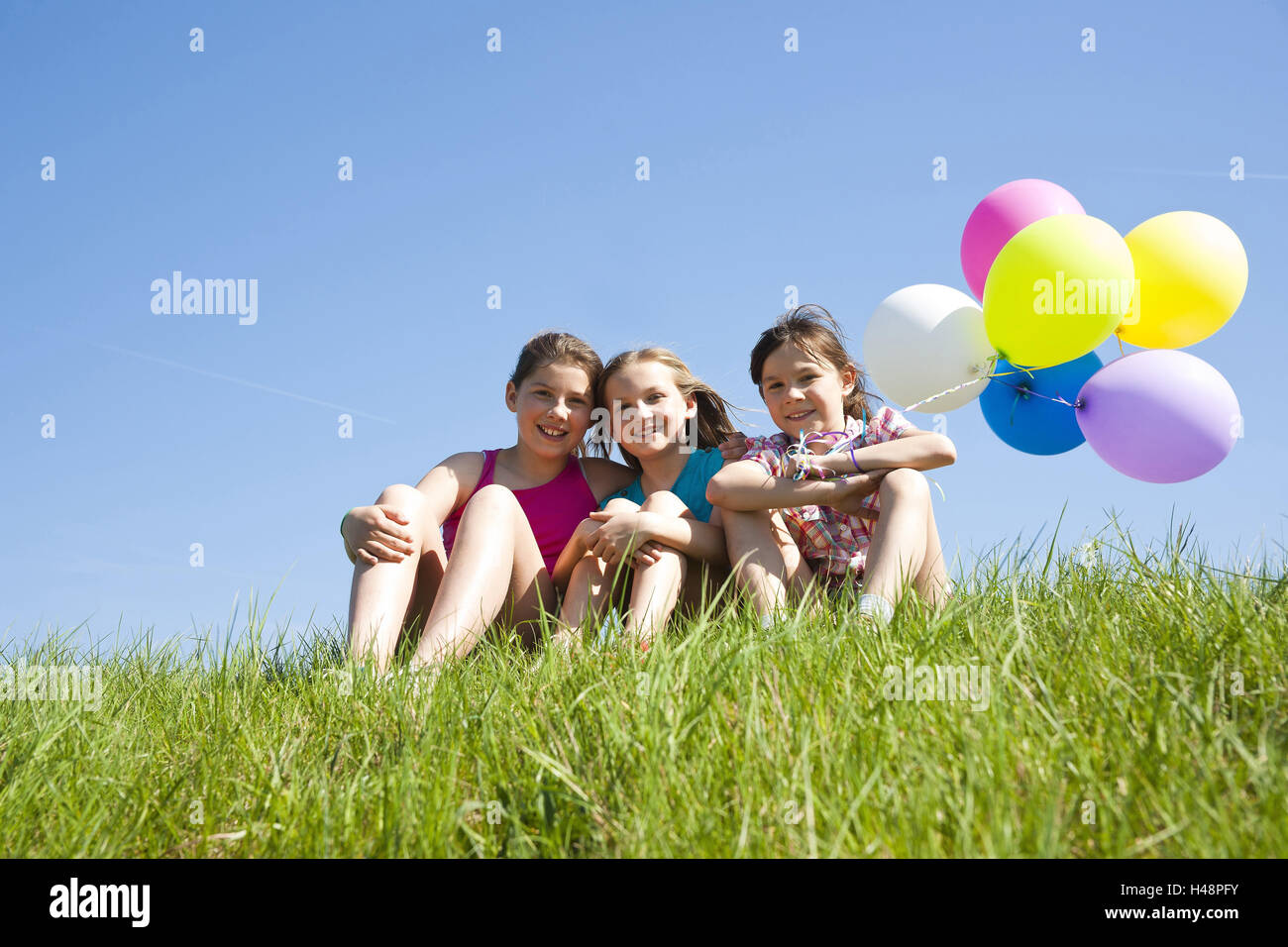Trois jeunes filles s'asseoir avec des ballons sur un pré, Banque D'Images