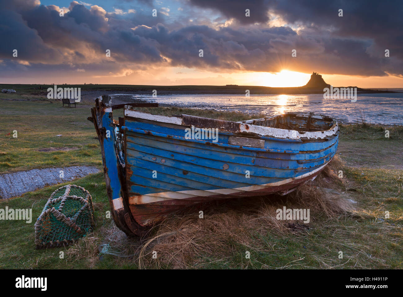 Bateau de pêche abandonnés sur l'Île Sainte à l'aube, avec au-delà de Château de Lindisfarne, Northumberland, Angleterre. Printemps (mars) 2014. Banque D'Images