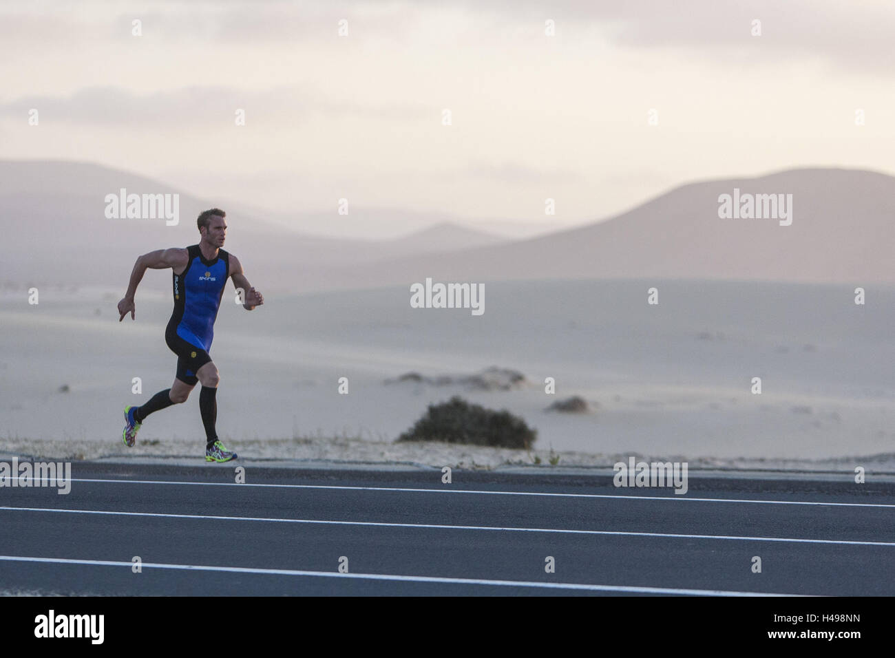 Sprints coureur sur route asphaltée entre les dunes de sable, Fuerteventura Banque D'Images