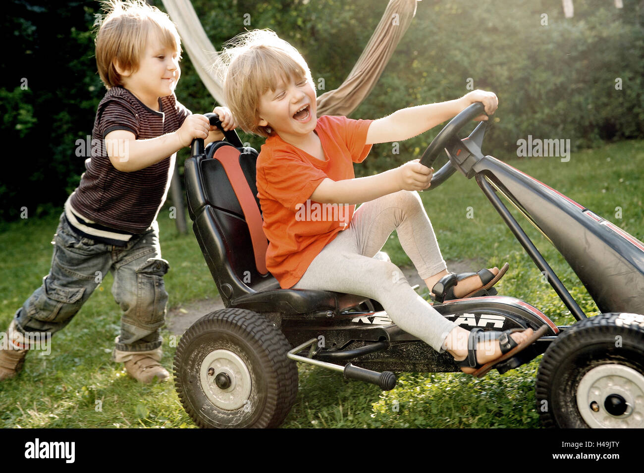 Deux enfants jouant avec Kettcar dans le jardin, Banque D'Images