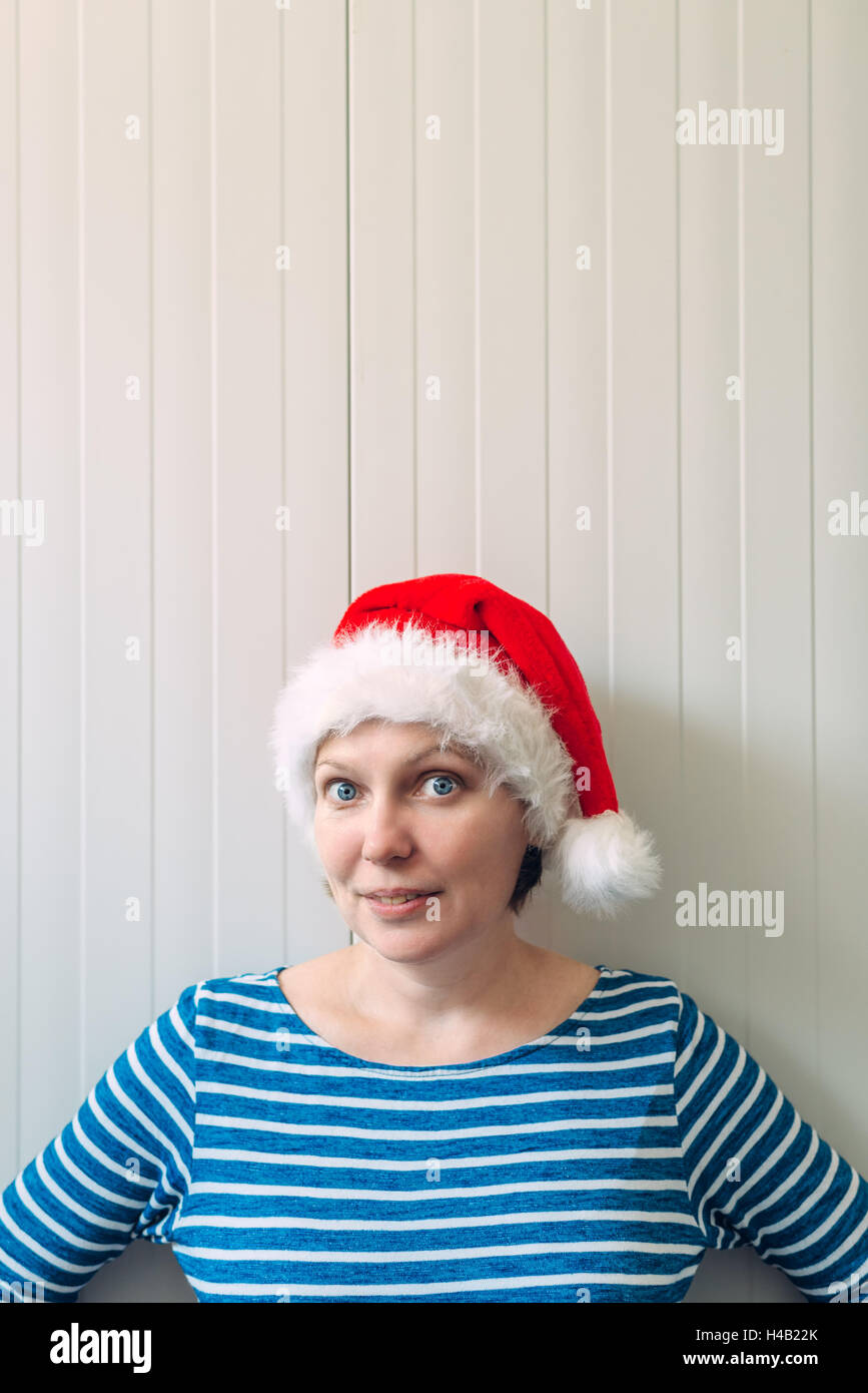 Portrait of smiling caucasian woman adultes belle avec Santa Claus hat contre mur en plastique blanc comme copy space Banque D'Images