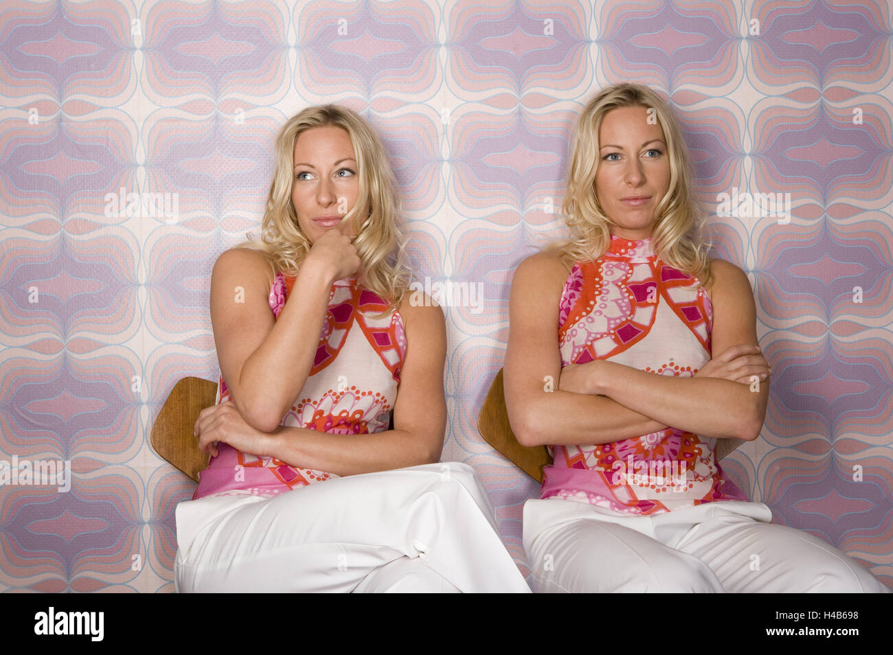 Les femmes, des jumeaux, des tenues, des chaises, assis, personnes, deux, poil long, blond, vêtements, top, top, coloré, à motifs, de couleur, rouge, orange, attendre le Doppelganger, sœurs, litige, silence, double exposition, Banque D'Images