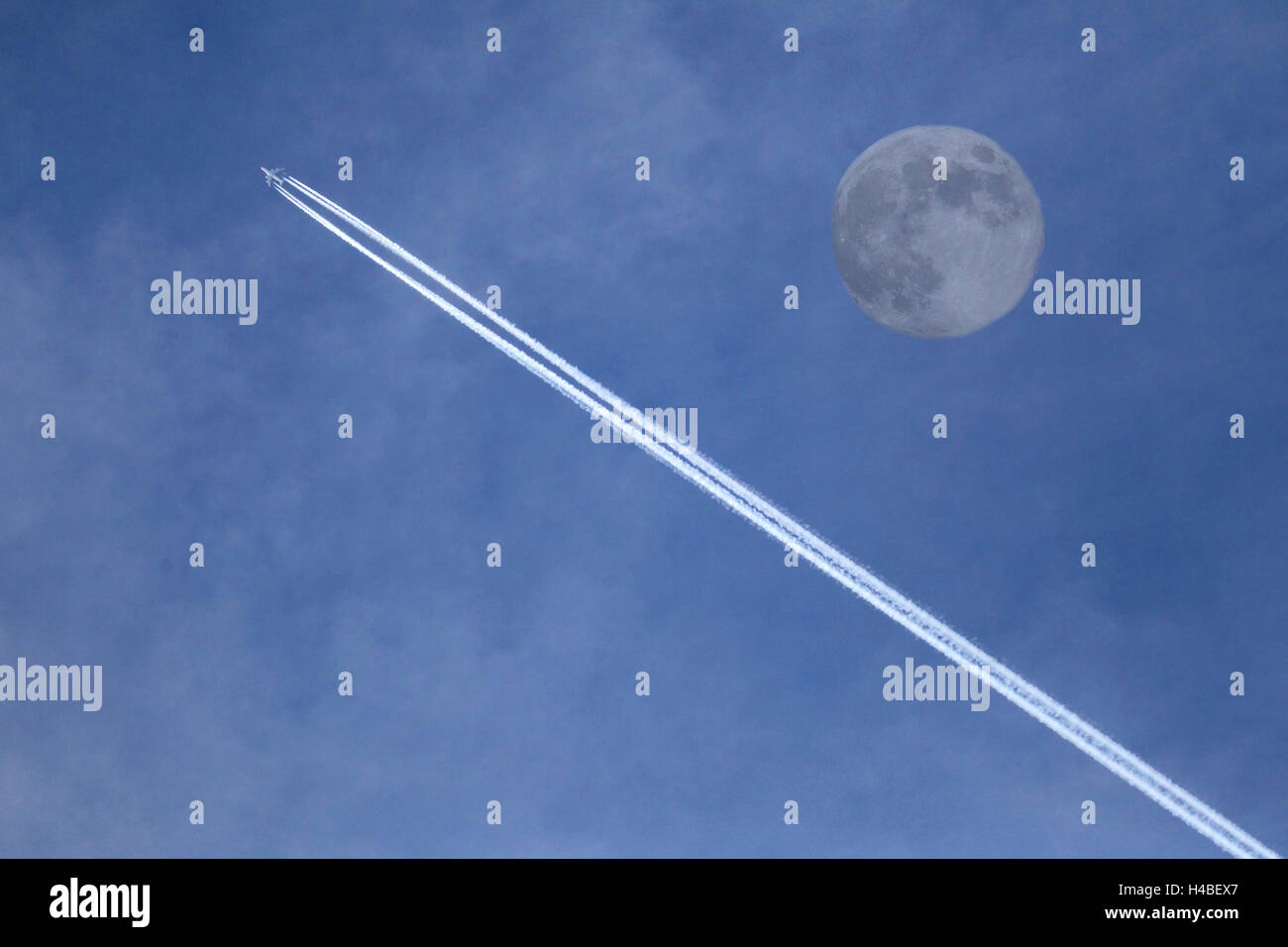 Jet avec bandes de condensation et la lune [M] Banque D'Images