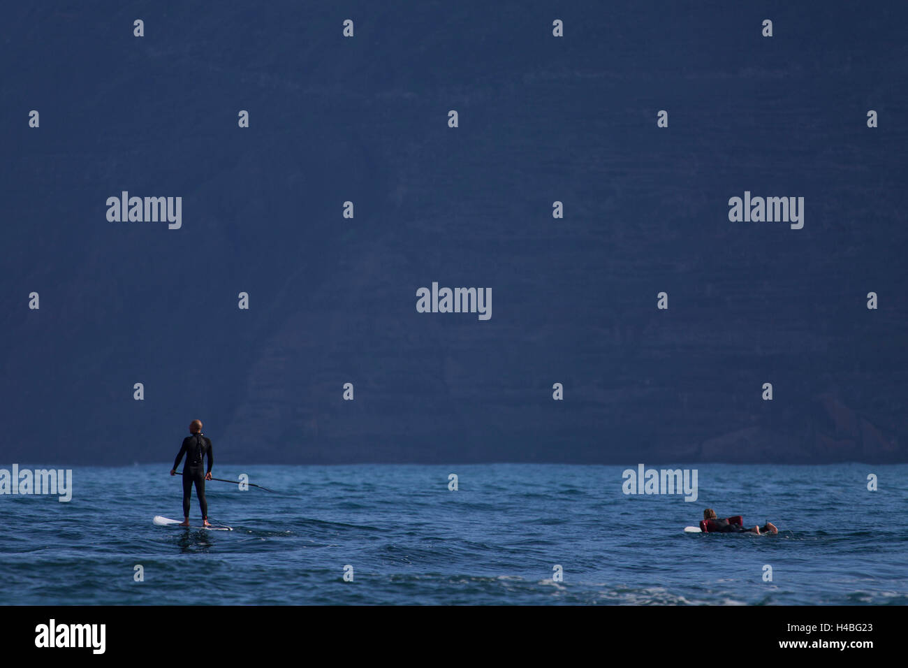 Paddleboarder debout et surfer en attente d'une vague Banque D'Images