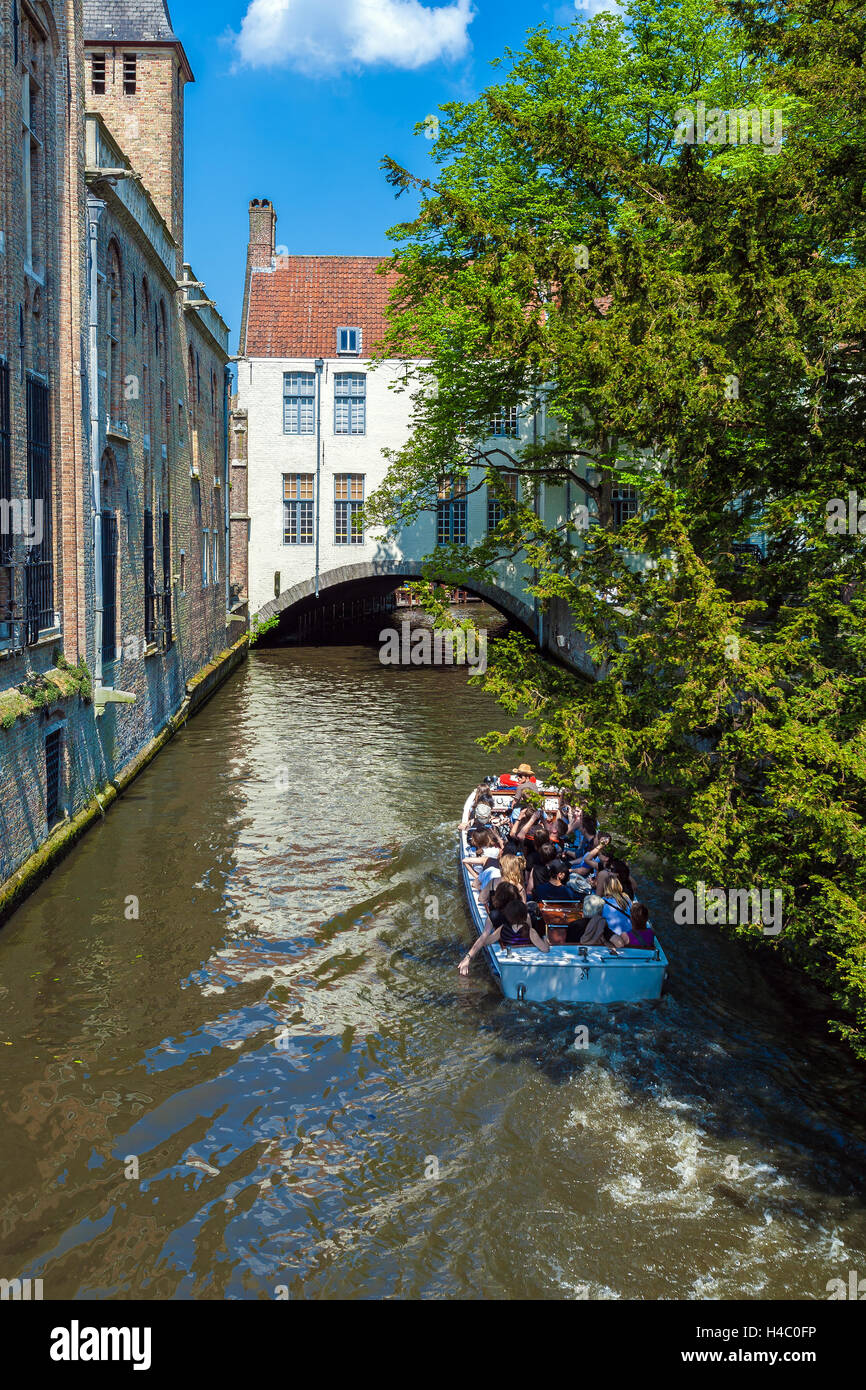 BRUGES, BELGIQUE - 6 avril 2008 : les touristes flottent sur un bateau à travers le canal près de gîtes Dijver Banque D'Images