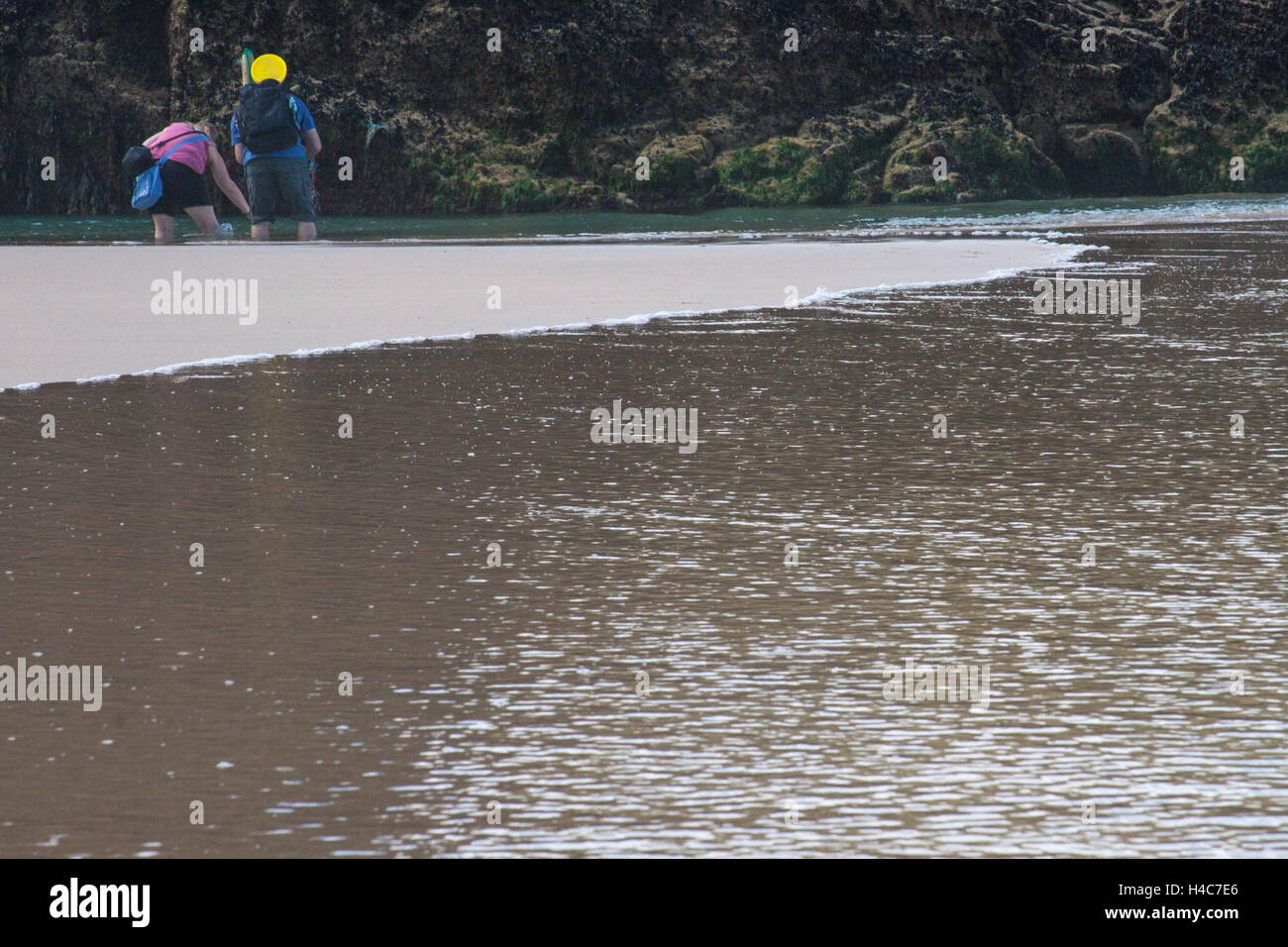 Un couple de touristes à recherche dans Cornish rock pools avec une marée montante. Banque D'Images