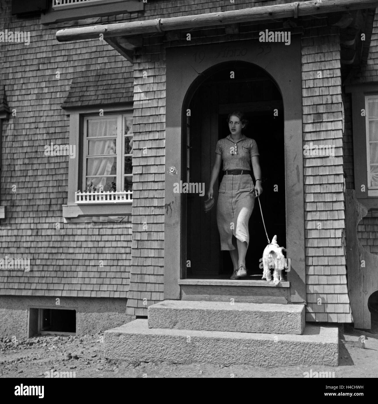 Eine junge Frau mit einem verläßt Foxterrier das Haus, Deutschland 1930 er Jahre. Une jeune femme de quitter la maison avec un chiot fox terrier, Allemagne 1930. Banque D'Images
