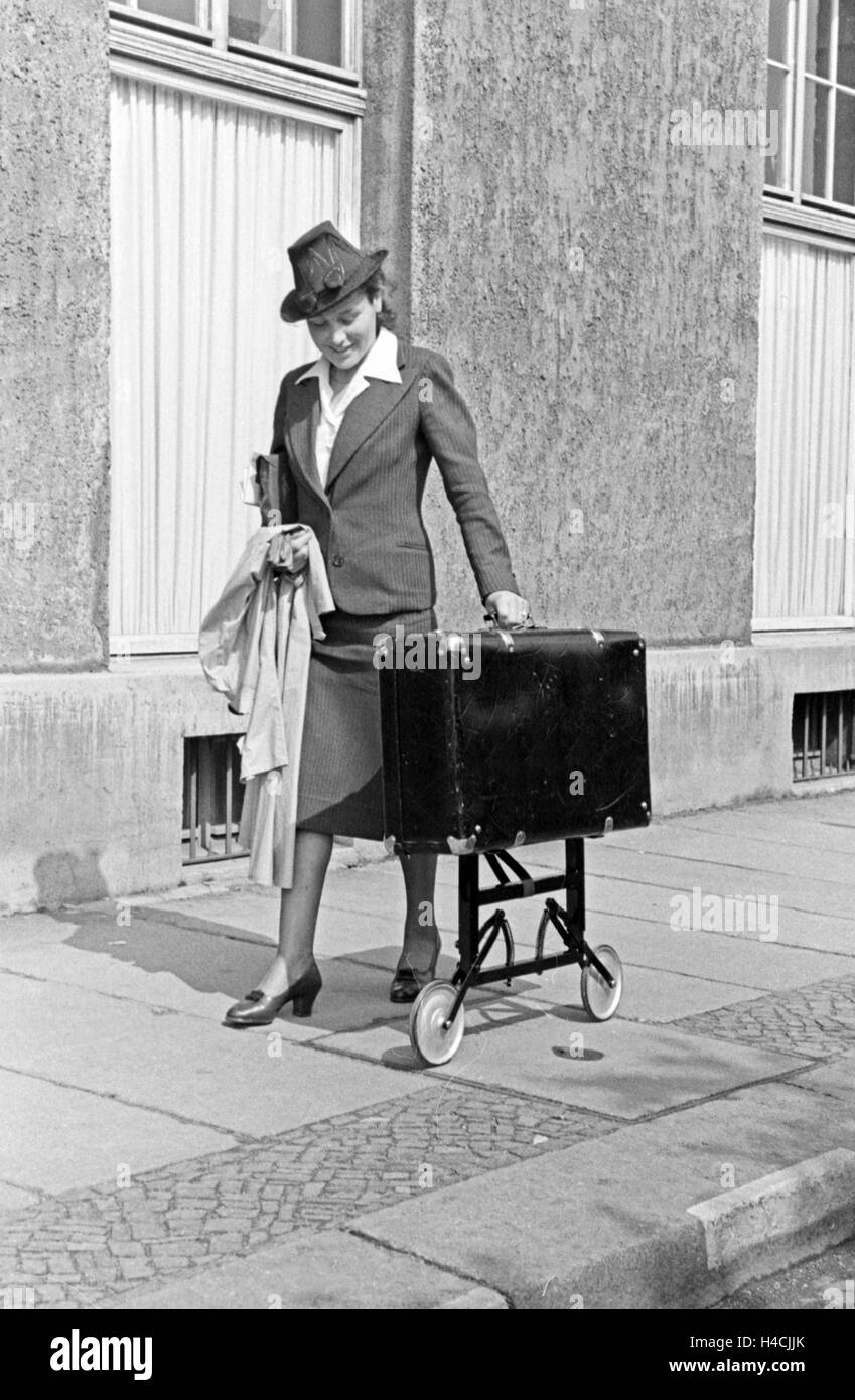 Eine Frau mit einem Koffer auf Rollen bei der Messe Leipzig, Deutschland 1940 er Jahre. Une femme avec une valise à roulettes au salon de Leipzig, Allemagne 1940. Banque D'Images