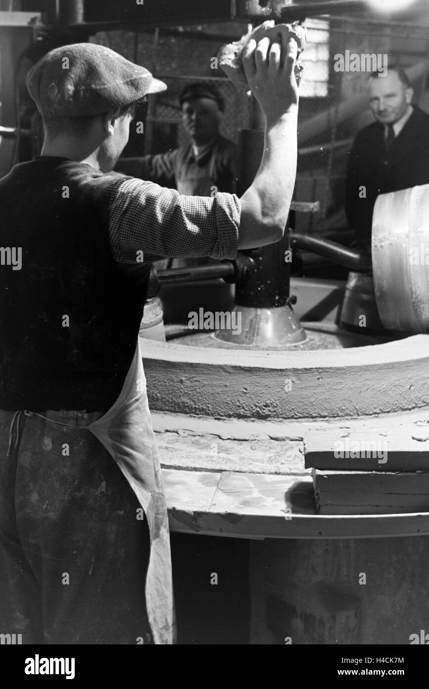 Keramiker der Staatlichen Porzellanmanufaktur stellen mit einer Knetmaschine Berlin tonne aus den Rohmaterialien zusammen, Deutschland 1930er Jahre. Céramistes de l'état d'argile Porcelaine Manufacture Berlin produire avec une machine à pétrir l'argile, l'Allemagne 193 Banque D'Images