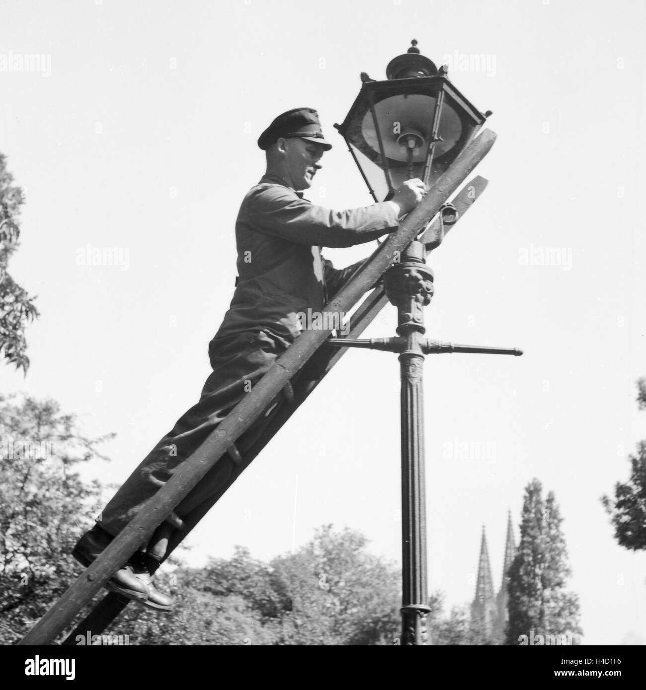 Ein städtischer Bediensteter wechselt defekte Glühbirnen von un Straßenlaterne aus Deutschland, 1930er Jahre. Un fonctionnaire de changer les ampoules cassées dans une rue lanterne, Allemagne 1930. Banque D'Images