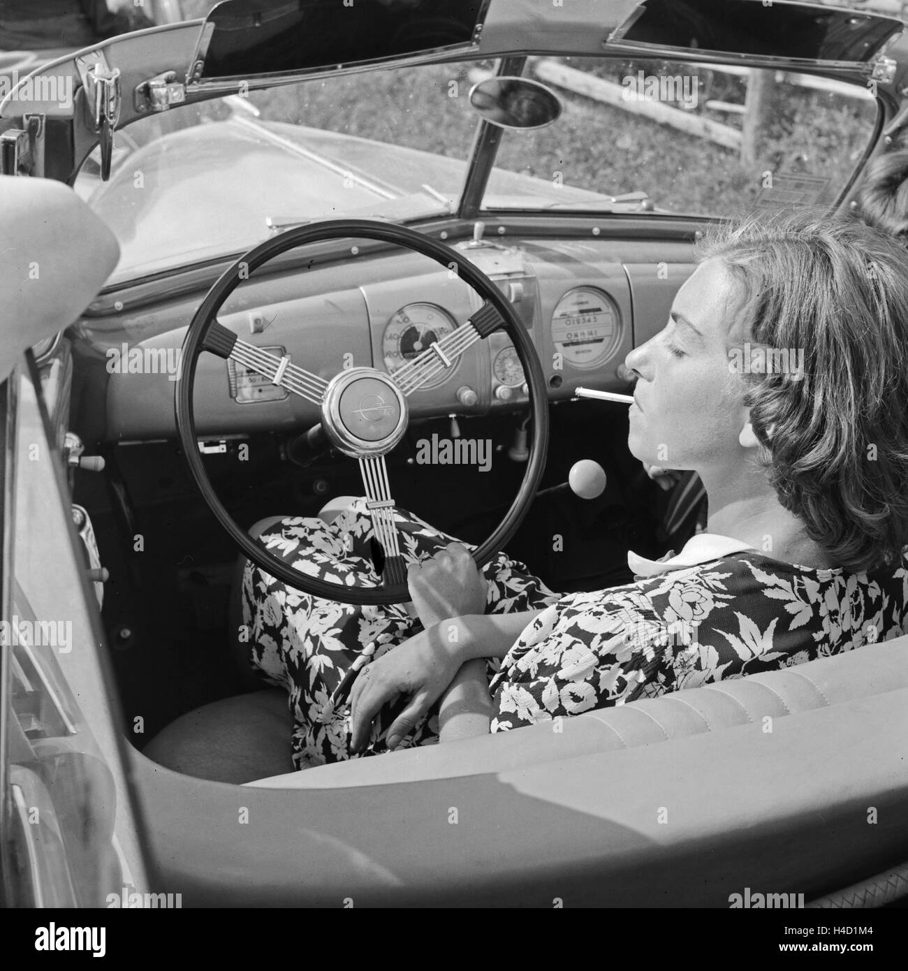 Eine junge Frau raucht am Steuer von Opel Olympia, Deuitschland 1930er Jahre. Un ypung femme fumant dans son modèle Opel Olympia, Allemagne 1930. Banque D'Images