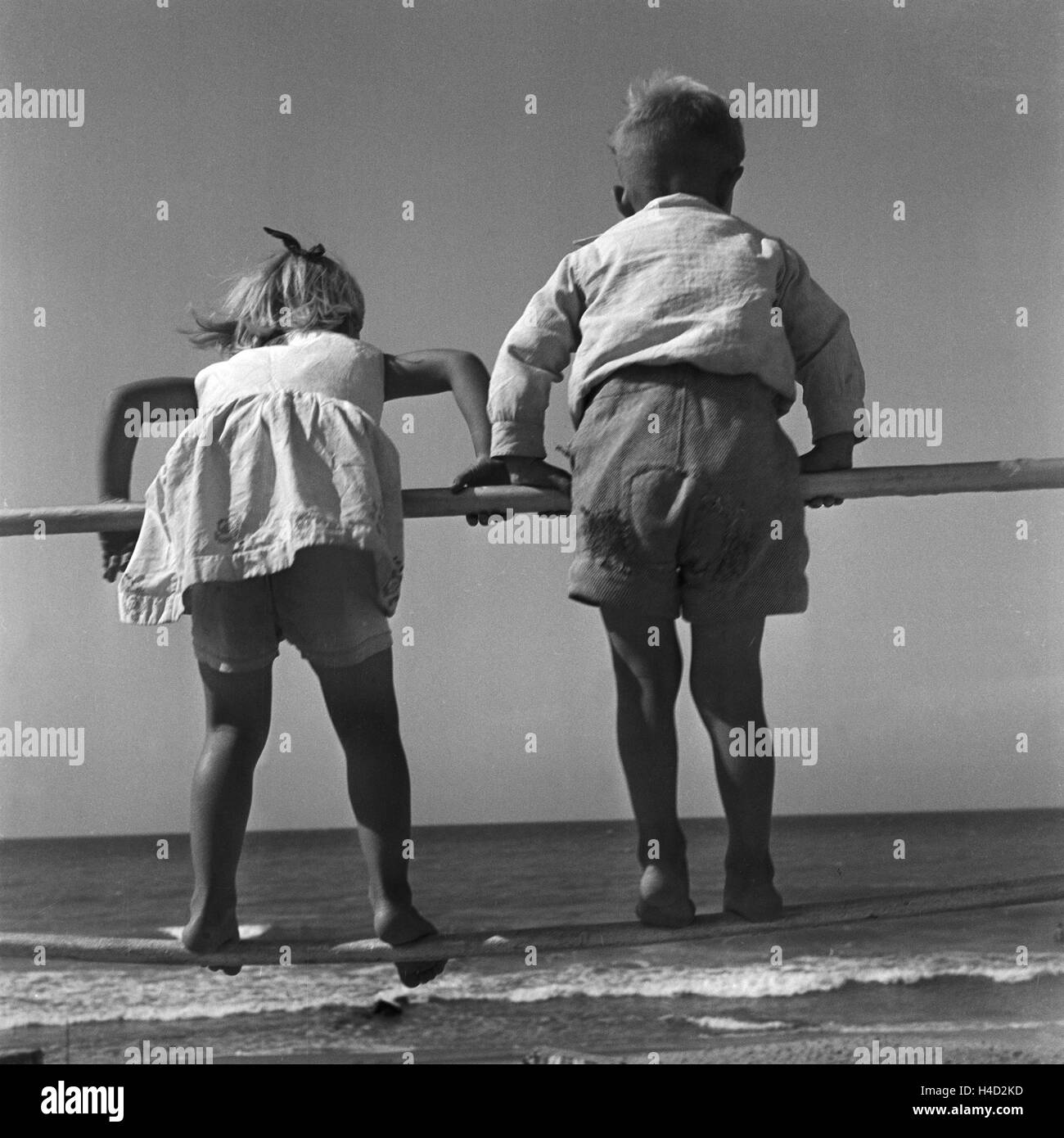 Zwei kleine Kinder turnen une einem Gelände am Strand der Ostsee dans Ostpreußen, Deutschland 1930er Jahre. Deux petits enfants jouant à une balustrade sur la côte de la mer Baltique à l'Est de la Prusse, l'Allemagne des années 1930. Banque D'Images