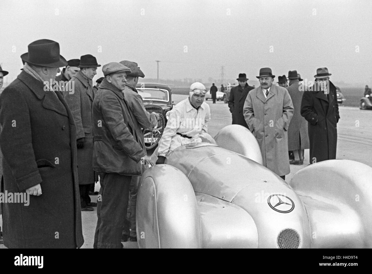 Le pilote automobile allemand Rudolf Caracciola s'élève dans l'habitacle Mercedes Benz W 125 en face de la tentative de record du monde, l'Allemagne des années 1930. Pilote de course allemand Rudolf Caracciola entrant dans la Mercedes Benz W 125 en face de l'essai record du monde, l'Allemagne années 30 voir. Banque D'Images