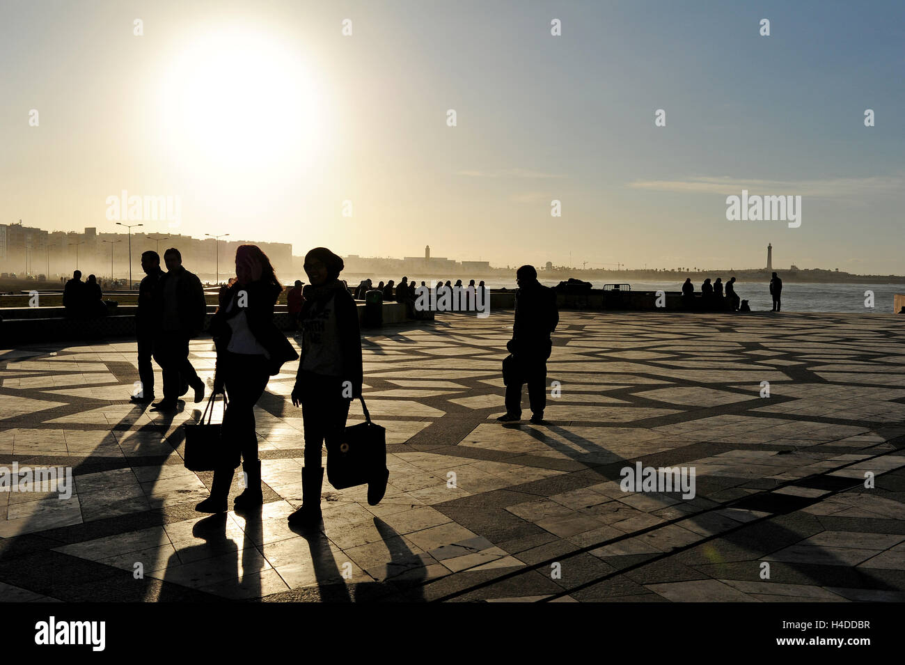 Personnes pour le coucher du soleil dans la grande esplanade de la mosquée Hassan II. Banque D'Images