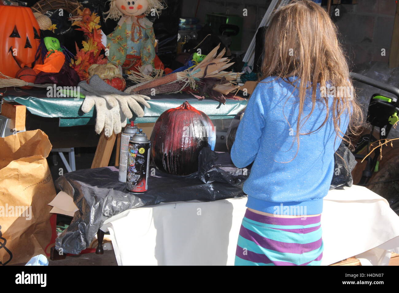 Jeune fille peinture par pulvérisation les citrouilles dans un affichage d'Halloween Banque D'Images