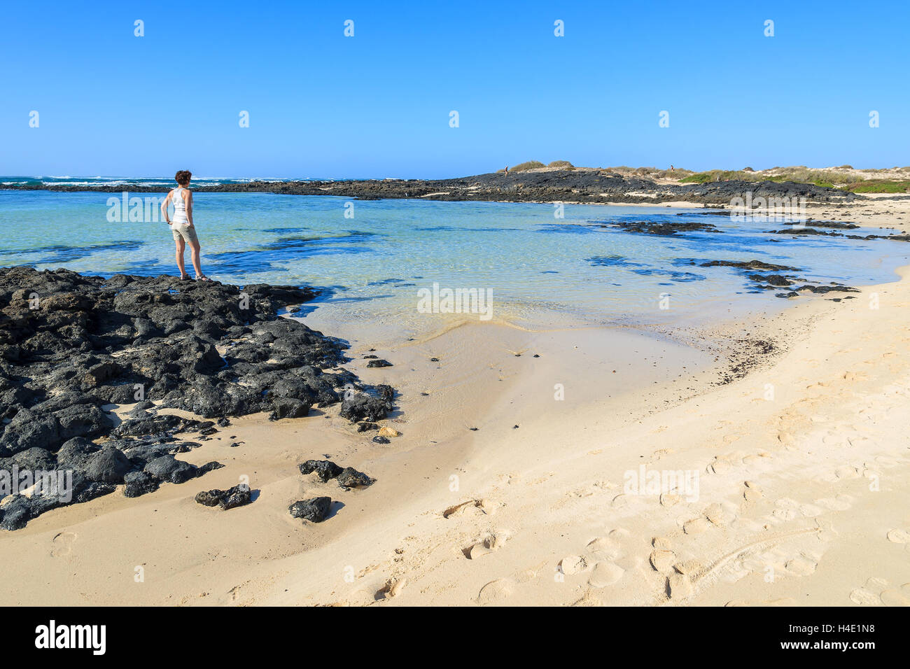 Les jeunes womand debout sur rock en plage de la lagune à El Cotillo, Fuerteventura, Îles Canaries, Espagne Banque D'Images