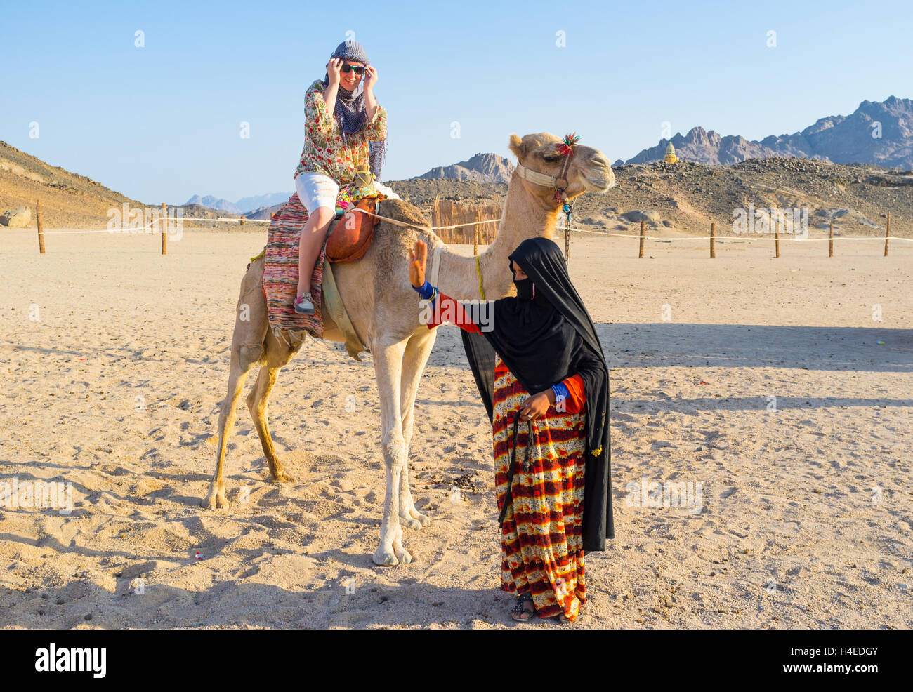 L'estime heureux pendant le tour de chameau et la jeune fille-chamelier vagues sa main à des amis, Sahara, l'Egypte Banque D'Images