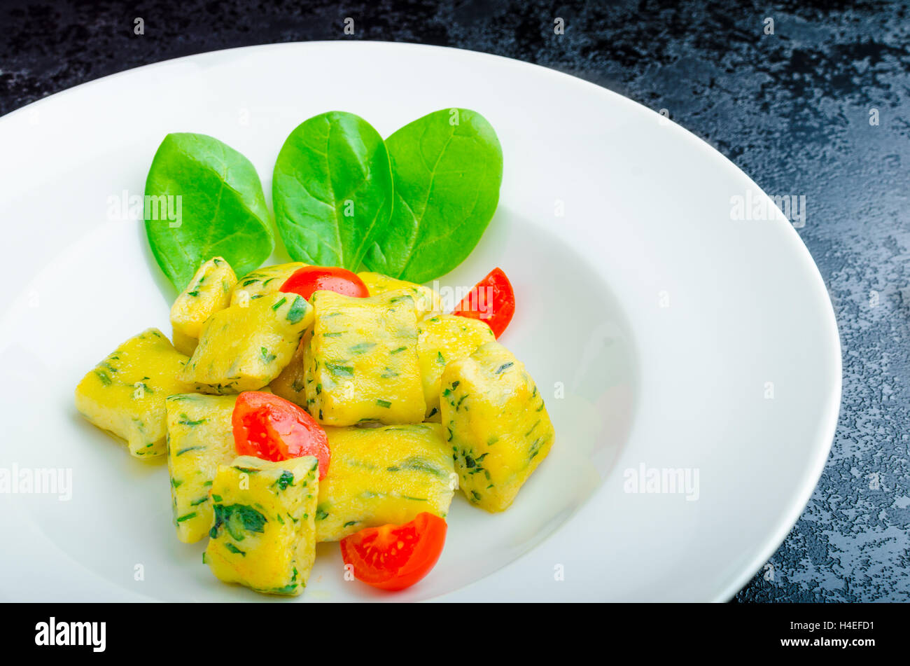 Gnocchi aux épinards avec du beurre fondu et les tomates cerise du jardin Banque D'Images