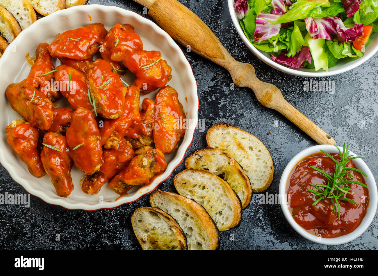 Petites ailes de poulet avec sauce à habanero épicé et salade mélangée avec des tomates cerises, baguette grillée avec de l'huile d'olive Banque D'Images