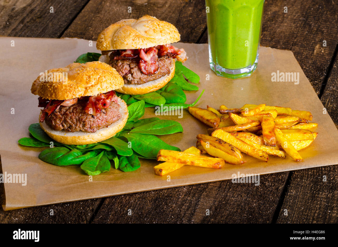 Bacon burger avec frites et herbes chili banana smoothie sur table en bois Banque D'Images