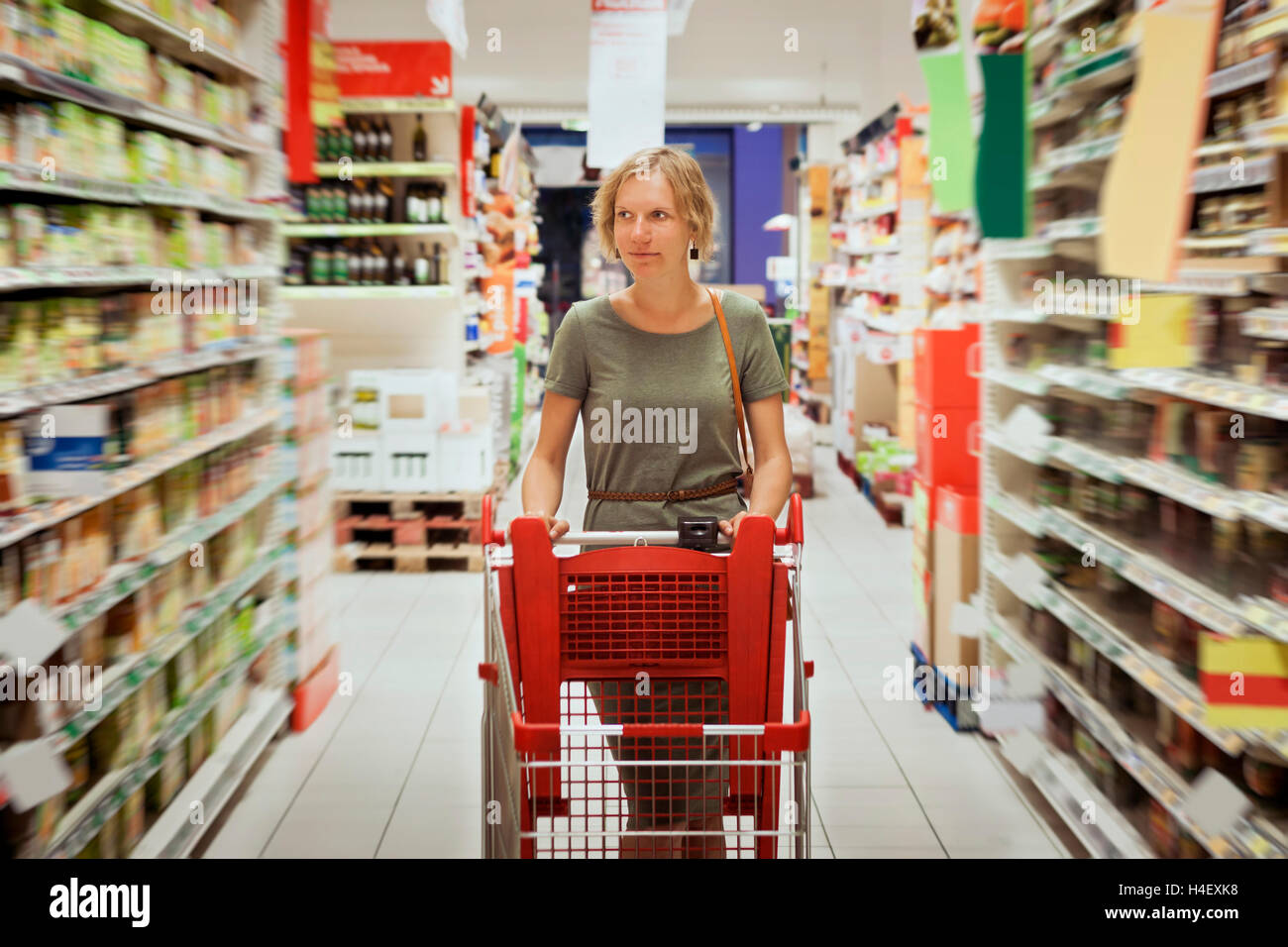 Femme souriante avec un panier au supermarché Banque D'Images