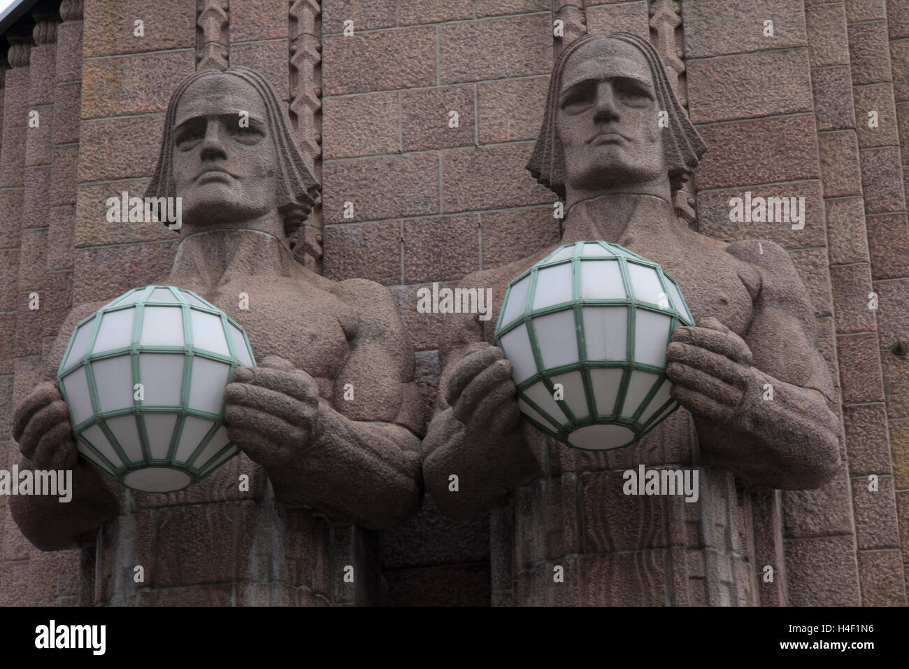Conçu en 1919 par le célèbre architecte finlandais Eliel Saarinen, Hesinki granit massif du rail station possède une paire de statues d'hommes. Banque D'Images