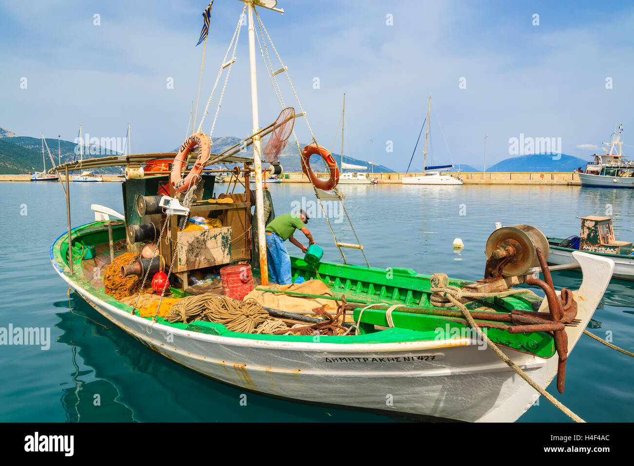 Le port de Sami, l'île de Céphalonie, Grèce - Sep 20, 2014 : pêcheur nettoie le bateau de pêche traditionnel grec à port de village sami. Bateaux colorés sont symbole d'îles grecques. Banque D'Images