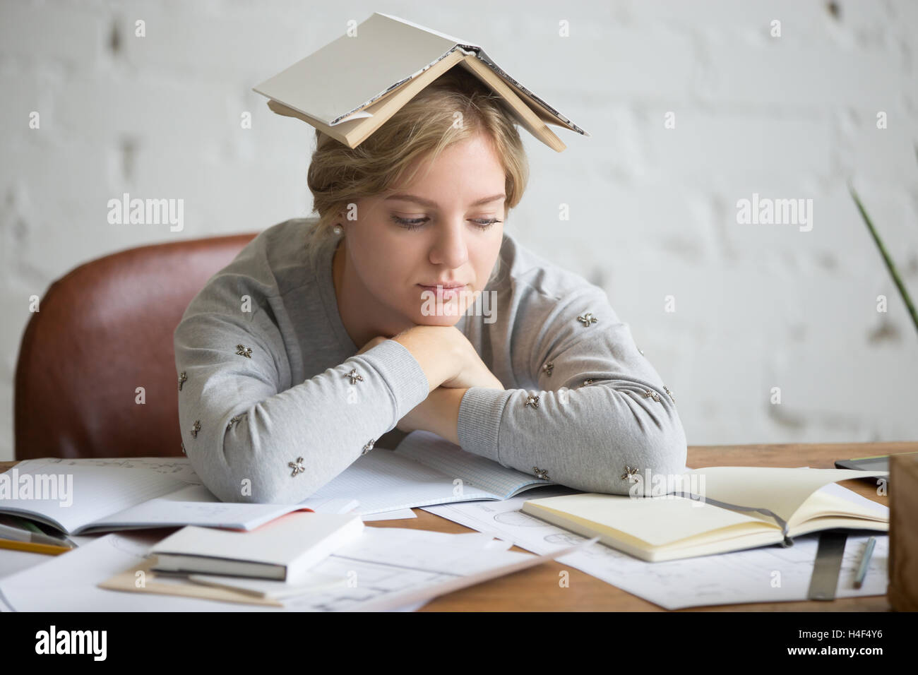 Portrait de jeune fille étudiante avec livre ouvert sur sa tête Banque D'Images