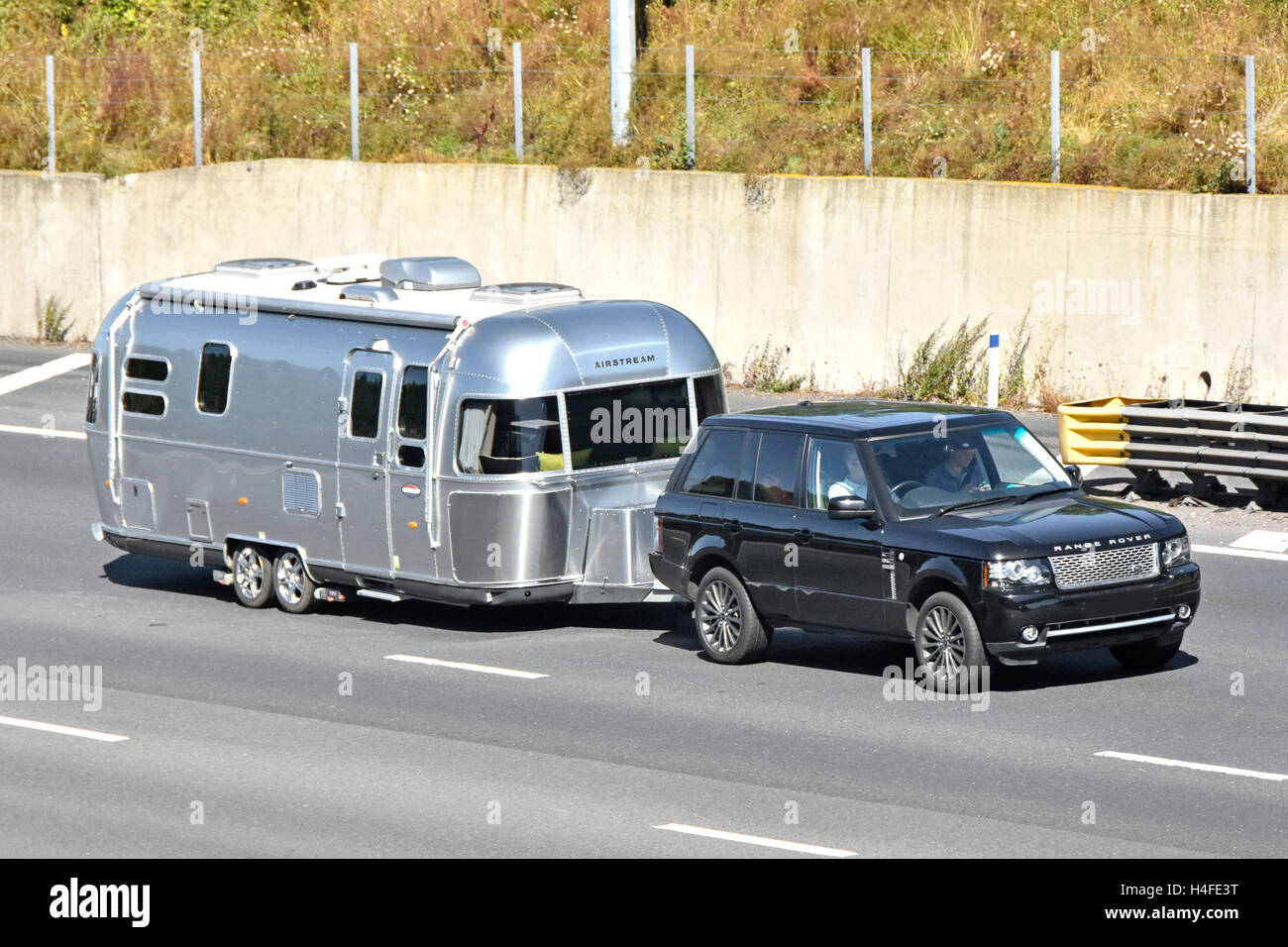 Conducteur et passager en voiture Range Rover caravane Airstream de remorquage en voiture sur l'autoroute BRITANNIQUE M25 plaque obscurci Banque D'Images