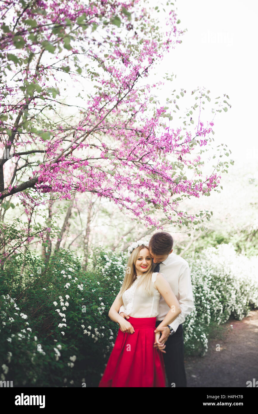 Jeune beau couple embrasser et s'étreindre près des arbres avec Blossom Park en été Banque D'Images