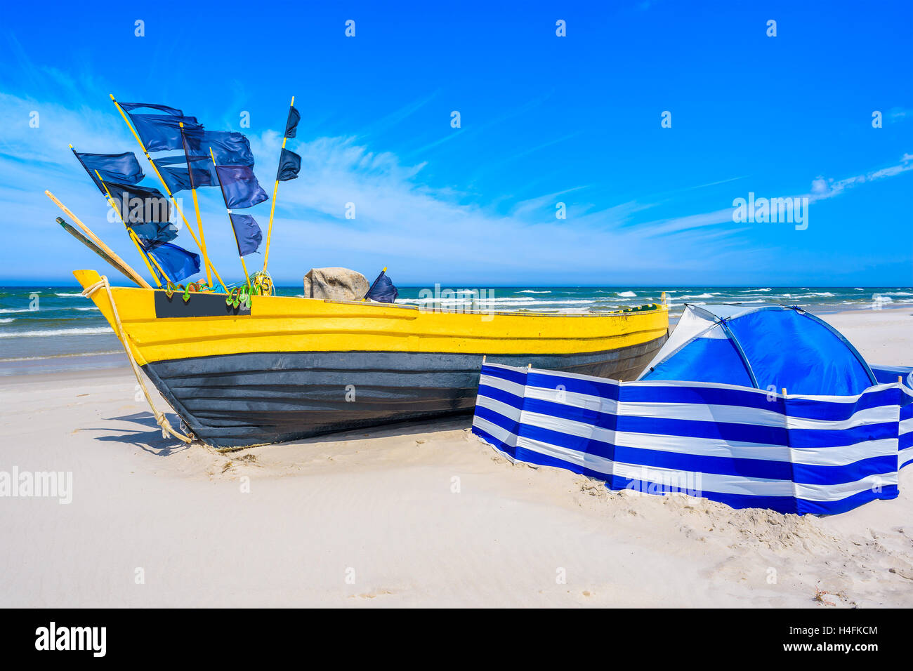 Bateau de pêche colorés et coupe-vent bleu avec tente sur la plage de sable de la mer Baltique, Pologne Banque D'Images