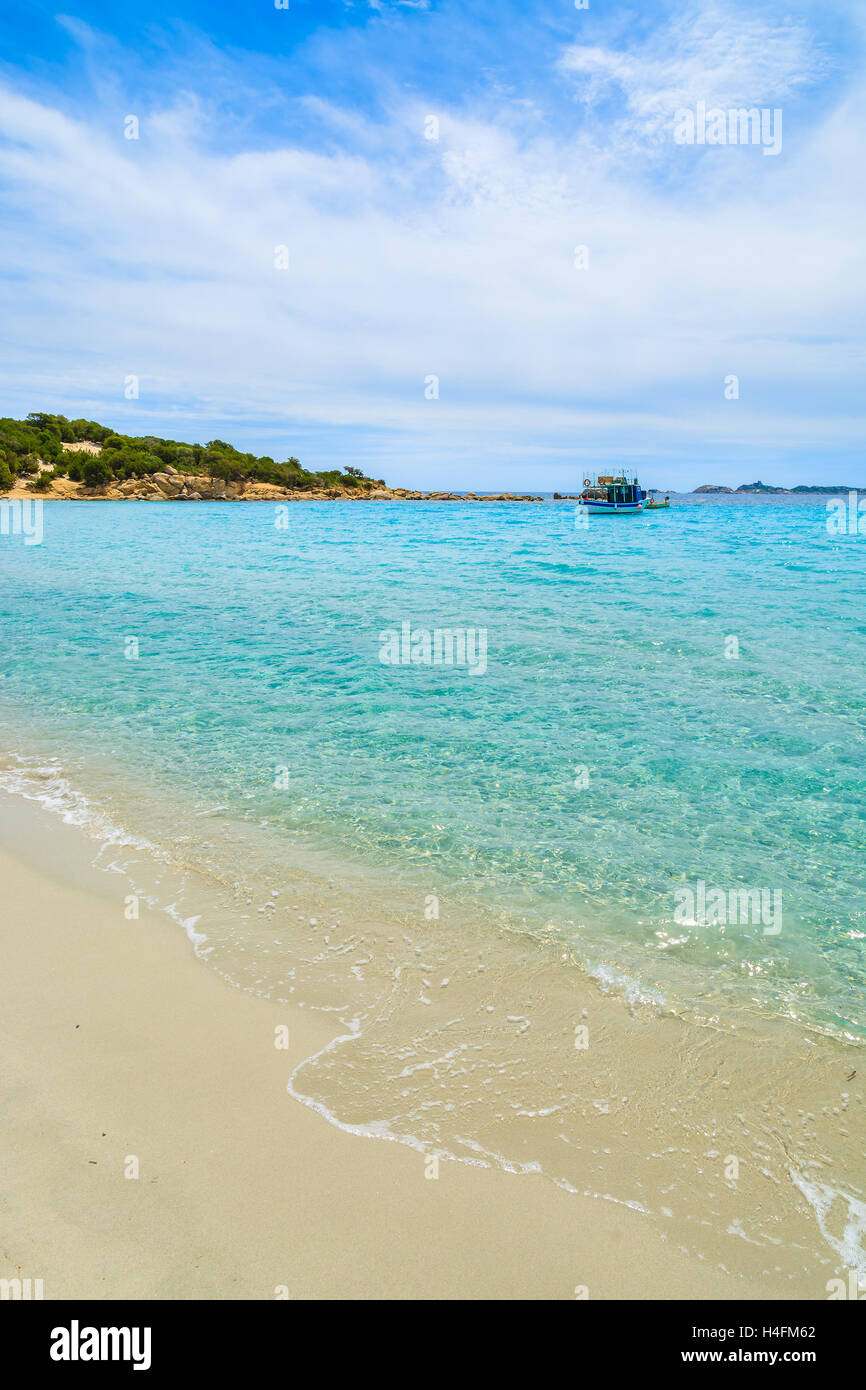 Belle plage avec l'eau de mer turquoise et de pêche bateau dans la distance, Cala Pira, l'île de la Sardaigne, Italie Banque D'Images