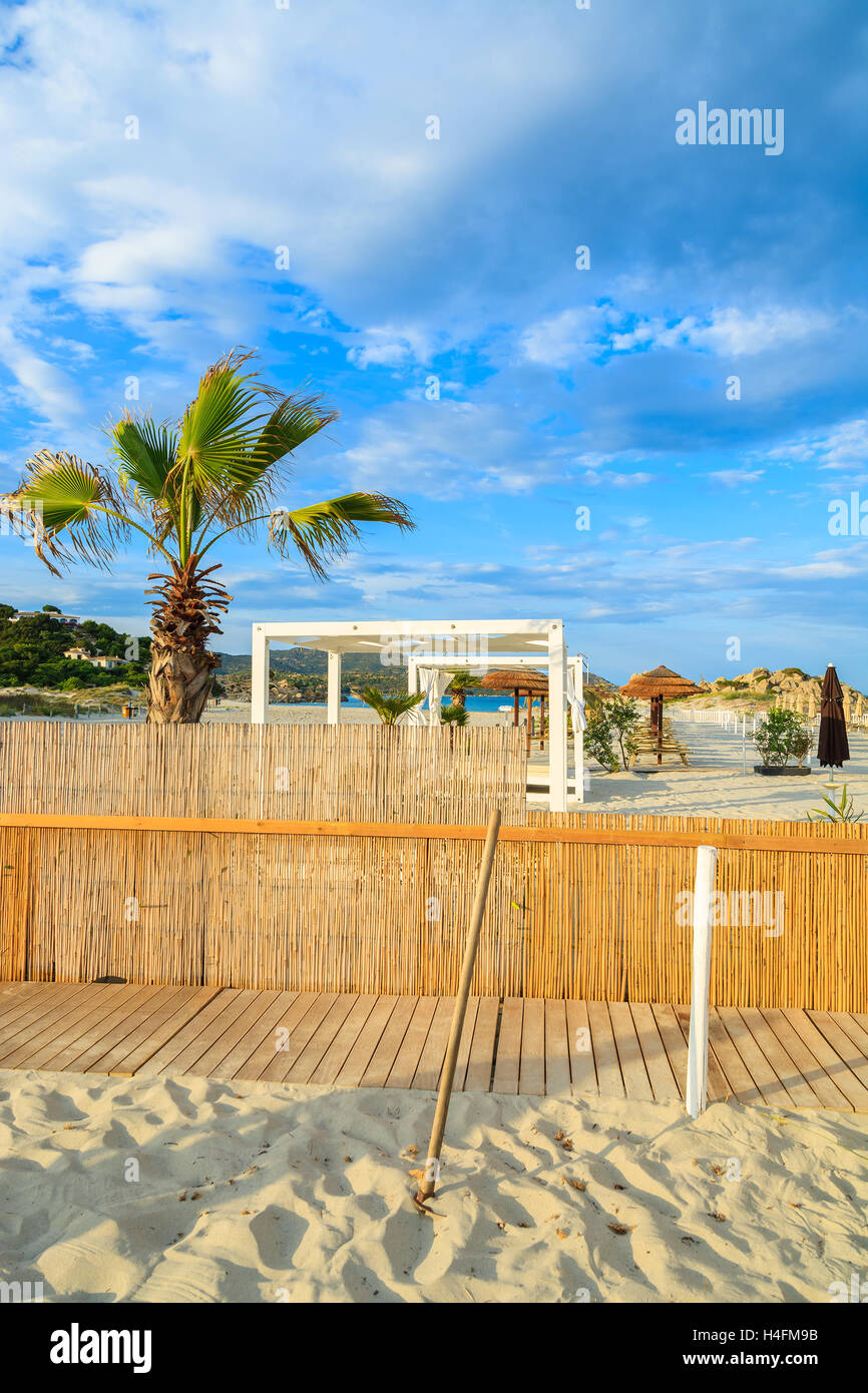 Clôture et palmier sur la plage de sable de Porto Giunco coucher du soleil chaud de la lumière, Villasimius, Sardaigne, île, Italie Banque D'Images