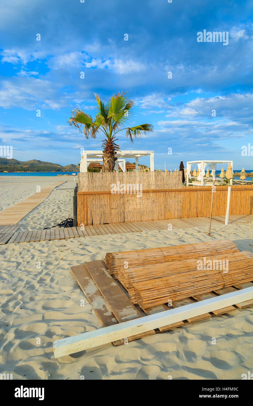 Clôture et palmier sur la plage de sable de Porto Giunco coucher du soleil chaud de la lumière, Villasimius, Sardaigne, île, Italie Banque D'Images