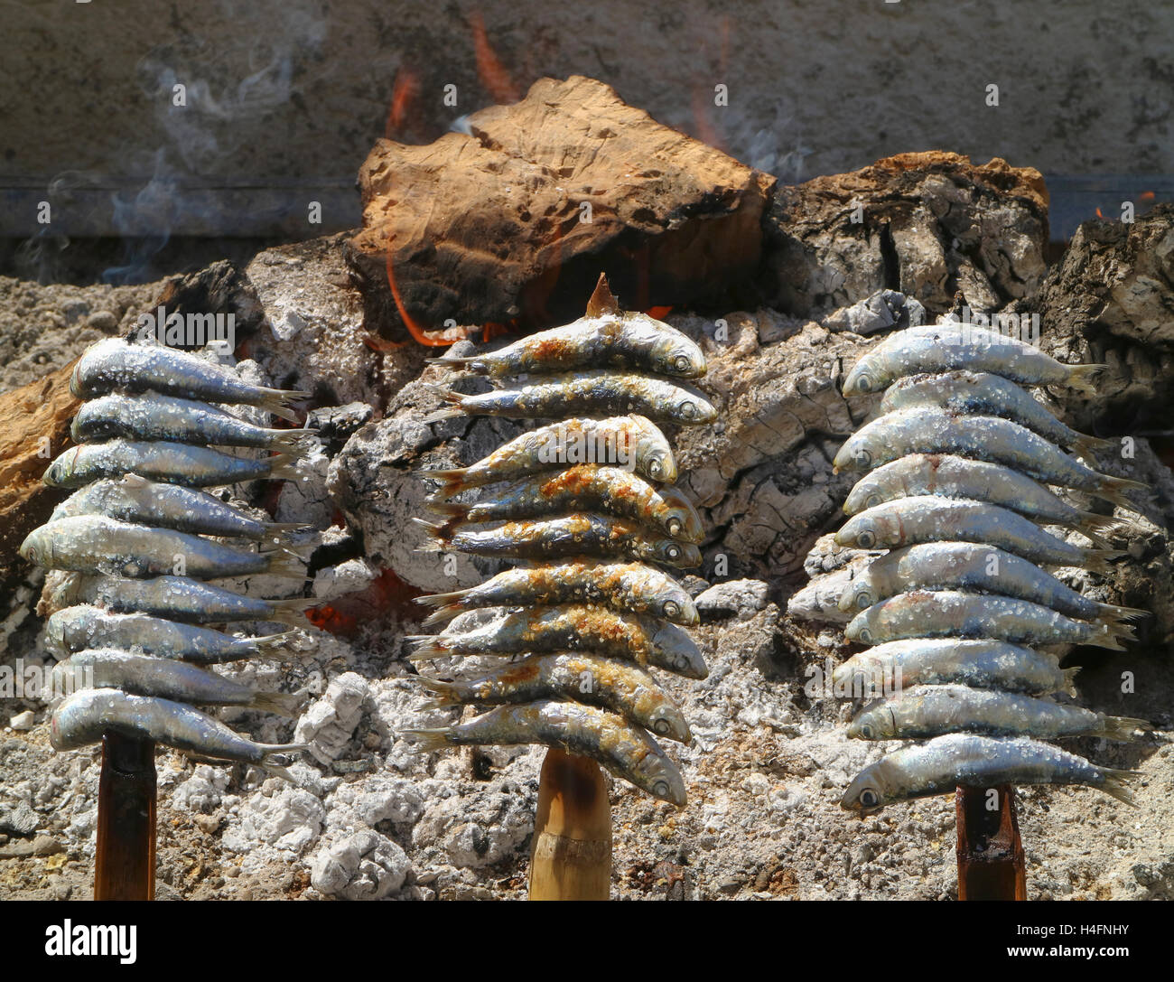 Brochettes, ou espetos, de sardines grillées sur un feu ouvert. Plat typique de la Méditerranée espagnole. Banque D'Images