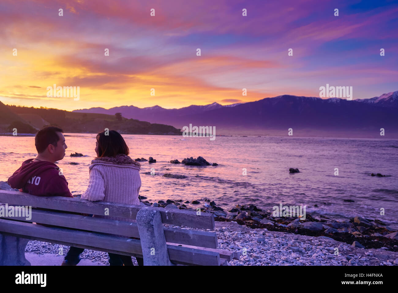 Couple assis sur le banc d'une conversation sous le coucher du soleil Banque D'Images