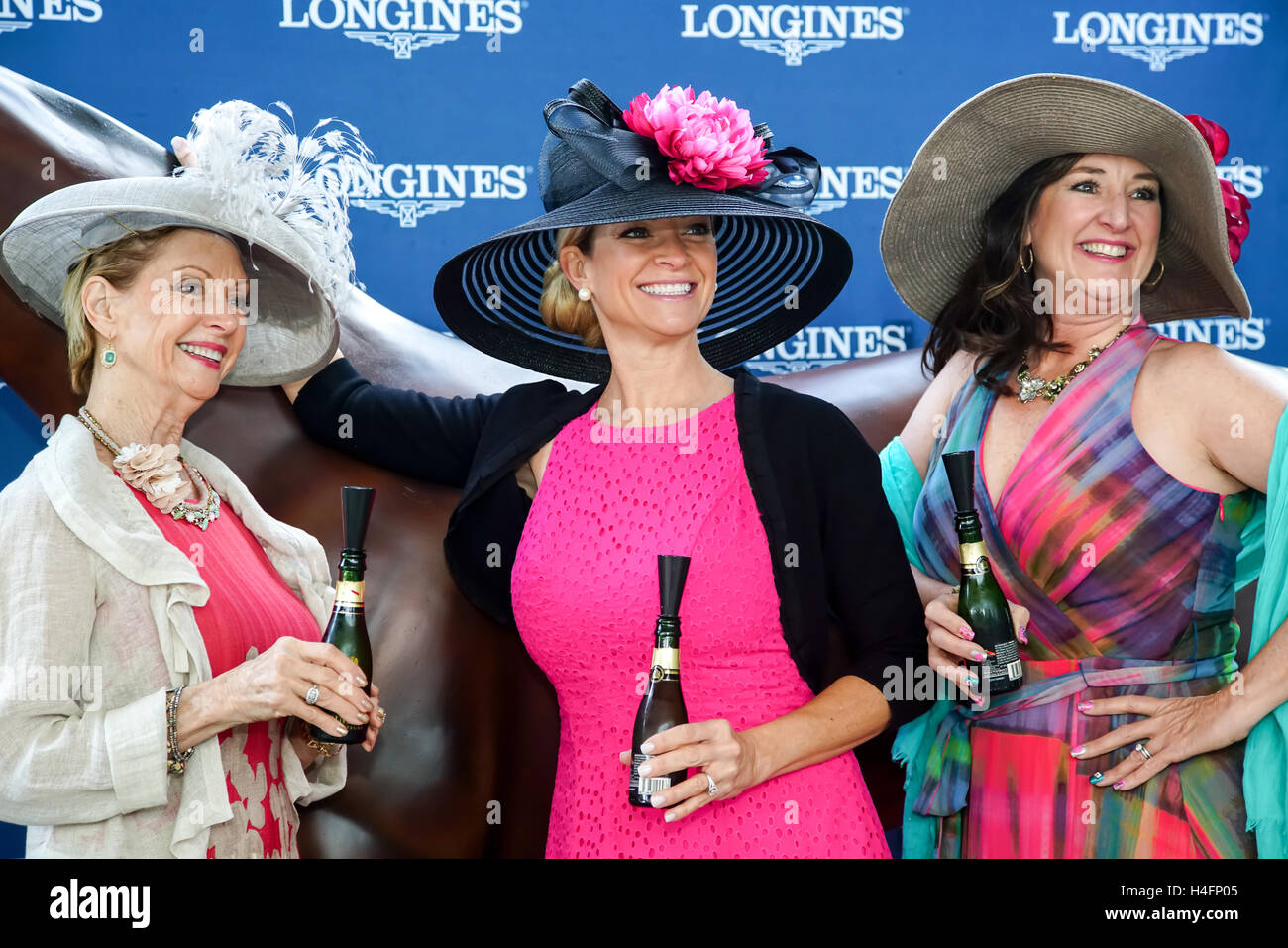 Dames posant avec mini bouteilles de champagne dans leurs chapeaux à Derby le pur-sang posing stand. Banque D'Images