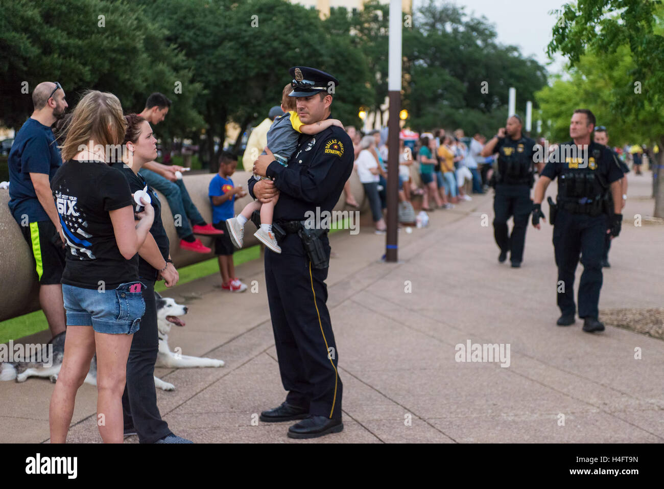 Un agent de police de Dallas un confort de l'enfant fatigué au Dallas Strong veillée aux chandelles le 11 juillet 2016 à Dallas, TX. Banque D'Images