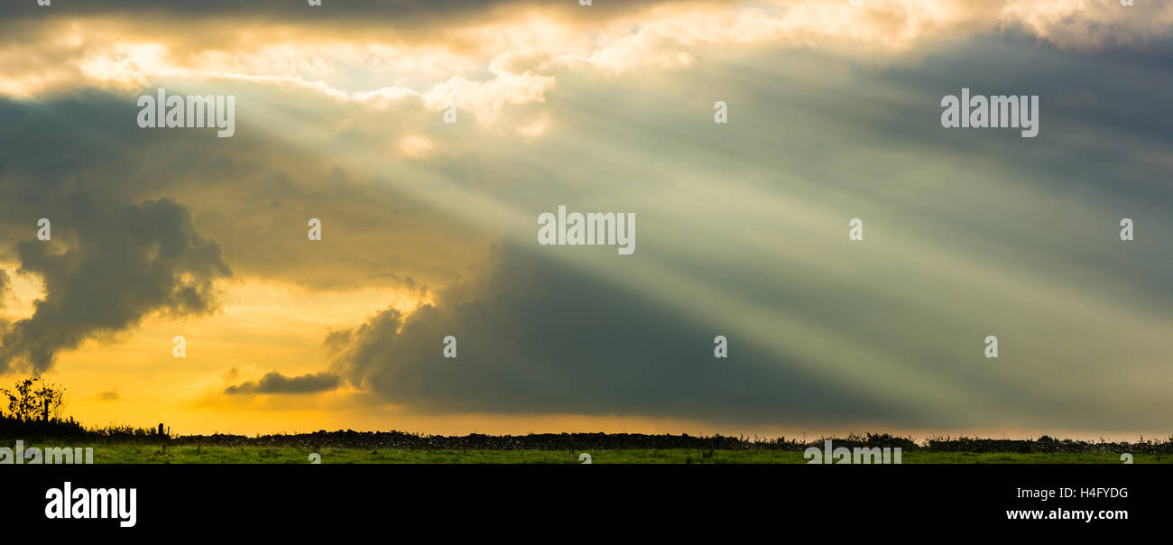 Les rayons du soleil de nuages au-dessus de champ et mur en pierre sèche. Ciel en colère impressionnante avec le soleil, au-dessus des pâturages dans la campagne anglaise Banque D'Images
