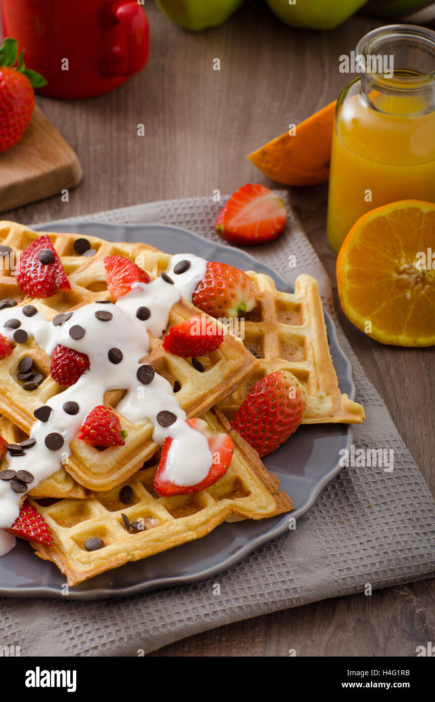 Gaufres maison au sirop d'érable et fraises, garni de crème et de chocolat, la boisson fraîche orange Banque D'Images