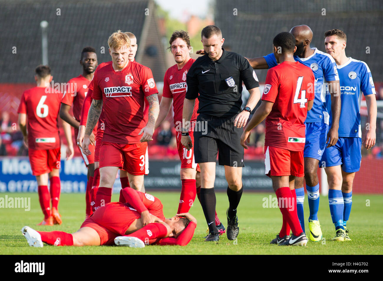 Les joueurs entourent l'arbitre après une faute laisse Alfreton Town's Adam Smith blessé sur le terrain Banque D'Images