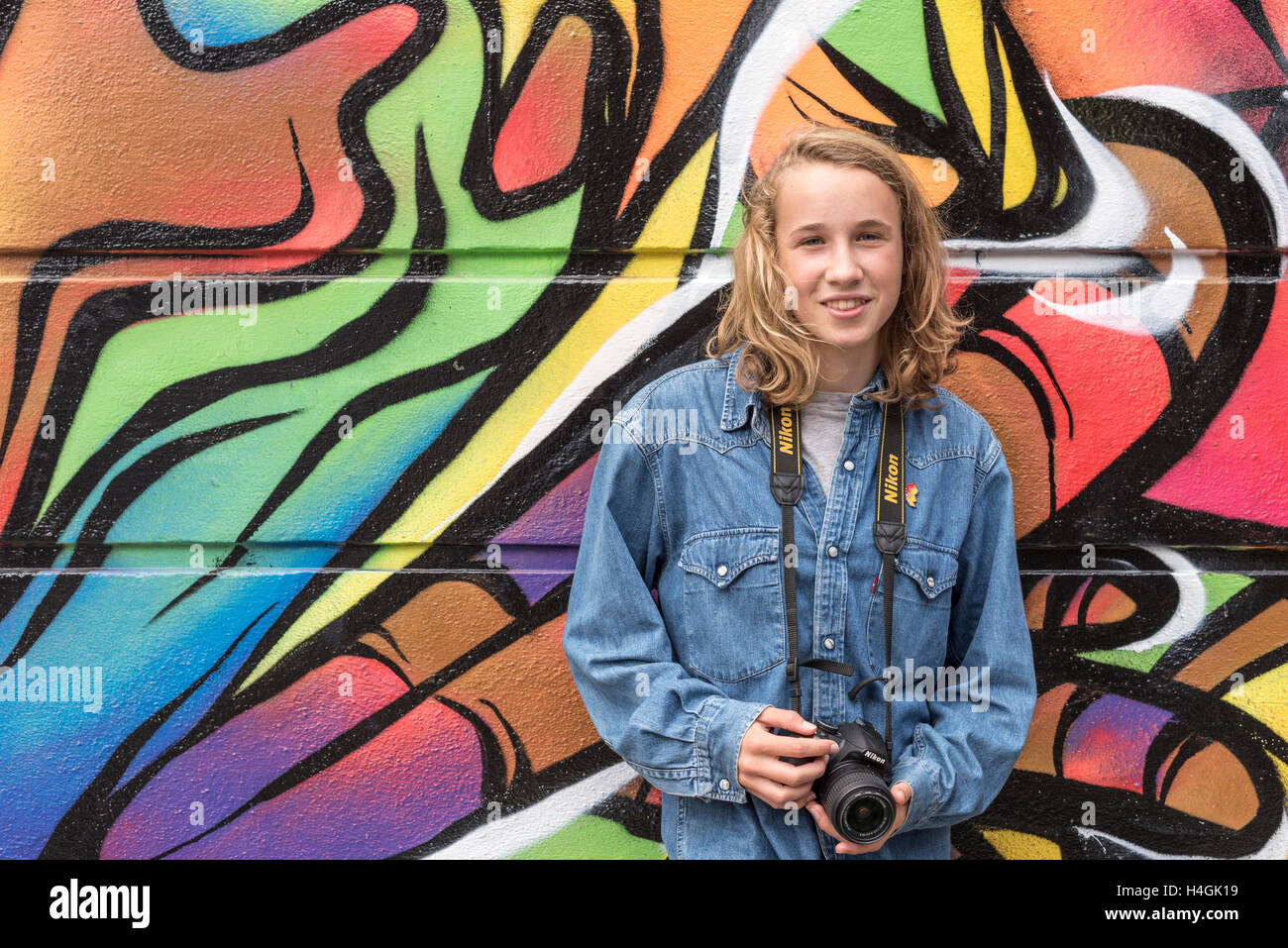 Fille avec une caméra debout contre un mur de graffiti sur elle Banque D'Images