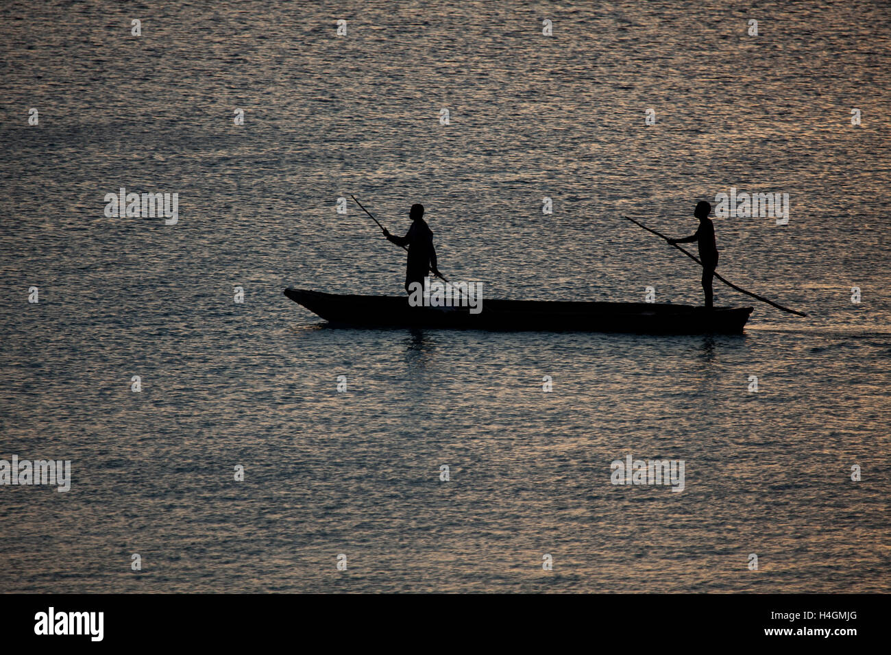 Une sombre silhouette de trois pêcheurs dans un combat dans le coucher du soleil lumière sombre. Banque D'Images